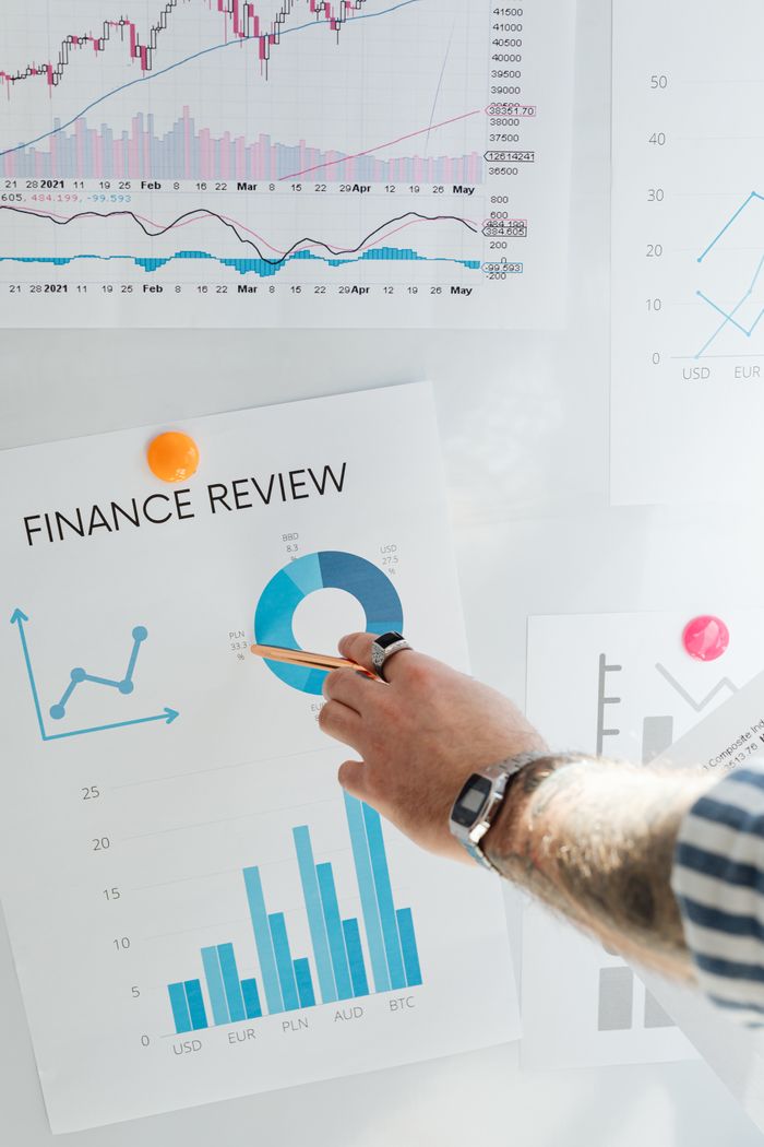 Un doigt pointe un graphique financier affiché au mur, pour illustrer l’analyse et l’examen des données.